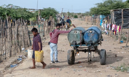 Two boys deliver water to a shack in La Pista.Water costs 3,000 pesos (about 5560p) a day for those who can afford it.