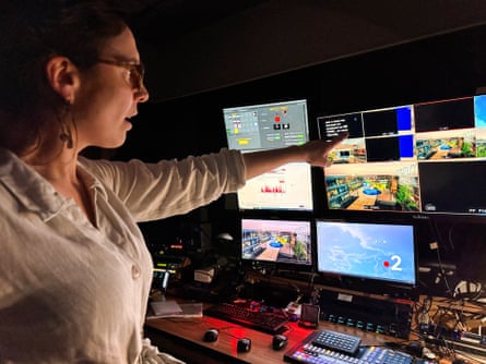 woman wearing glasses points to monitors