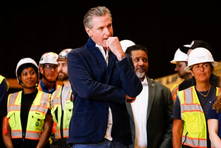 a man stands in front of people wearing reflective vests and hard hats