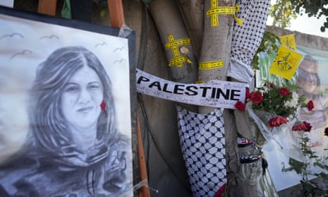 Yellow tape marks bullet holes on a tree and a portrait and flowers create a makeshift memorial, at the site where Shireen Abu Akleh was killed in the West Bank.