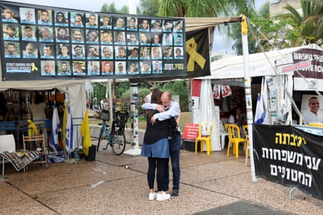 Israelis hug next to banner with photos of hostages at the Hostages square in Tel Aviv on Thursday.