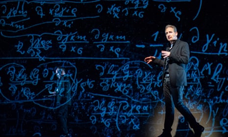 brian greene giving a lecture strolling on a big stage backlit with equations