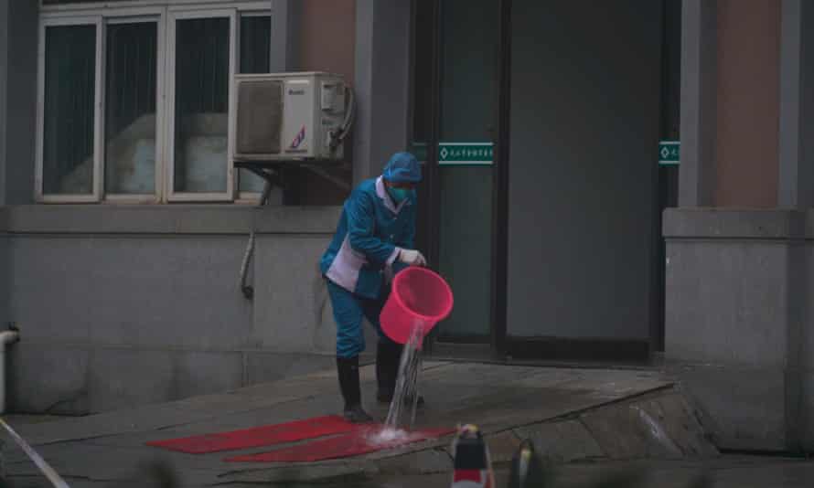 Hospital staff wash the emergency entrance of Wuhan Medical Treatment Center, where some infected with the new virus are being treated