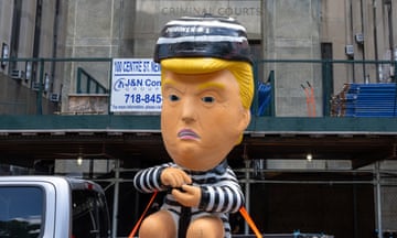 Inflatable showing Trump in a jail uniform is driven past court