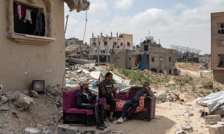 Palestinians sit on a sofa next to the ruins of their destroyed home in Khan Younis.