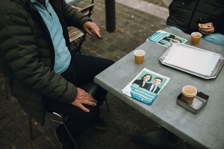 Two people sitting at an outside table with political flyers on it