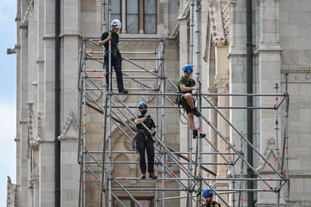 Workers stand on scaffolding with the parliament building behind