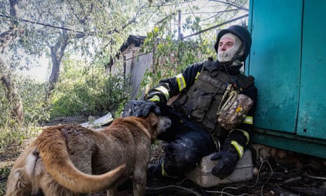 A firefighter pets a dog as he rests after putting out a fire in a private house hit by Russian shelling in Kharkiv on Friday.