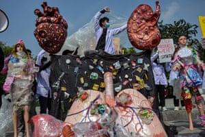 Environmental activists stage a protest featuring oversized models of human organs, lungs, heart, and kidneys, covered in plastic waste and sachets in Surabaya, Indonesia