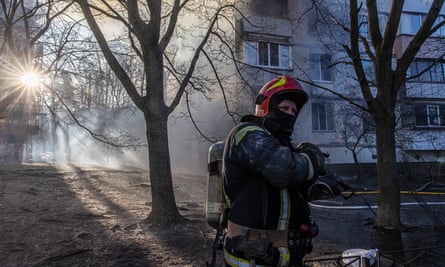 A firefighter stands next to a residential building which was hit by artillery in Kyiv on Tuesday.