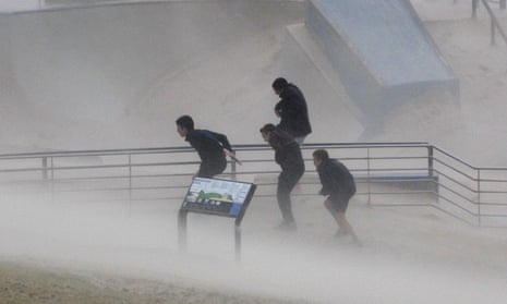 Boys try to take cover as heavy winds blow sand on to the promenade at Sydney’s Bondi Beach on Tuesday 21 April.