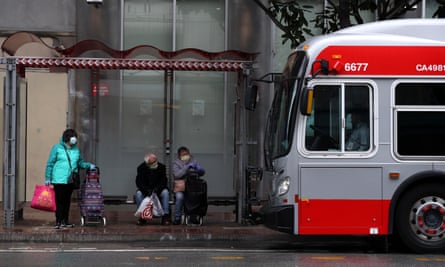 People wear masks as they wait or a San Francisco MUNI bus during the coronavirus pandemic on 6 April 2020 in San Francisco, California.