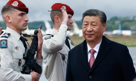 Two French soldiers one saluting with Xi walking past in black suit with pink tie