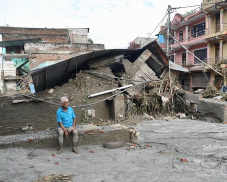 A local resident sits near a collapsed house lying deluged in sludge after the flash flooding at Devighat in Bidur municipality, Nepal’s Nuwakot district, on Thursday