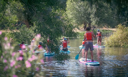 A paddleboard lesson on a pretty river with pink blossom.