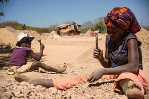 A child and a woman break rocks extracted from a cobalt mine in Lubumbashi, Democratic Republic of the Congo