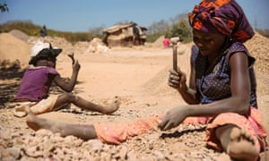 A child and a woman break rocks at a copper quarry and cobalt pit in Lubumbashi, DRC.
