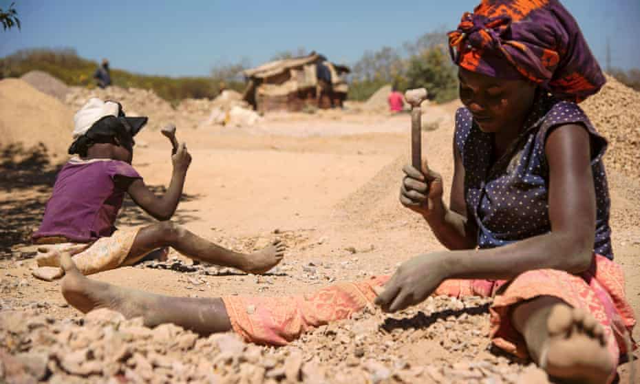 A child and a woman break rocks at a copper quarry and cobalt pit in Lubumbashi, DRC. 