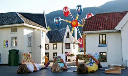 Children lie on their backs reading comics amid the quarter-size houses of the adventure park in Lilleputthamer, Norway.