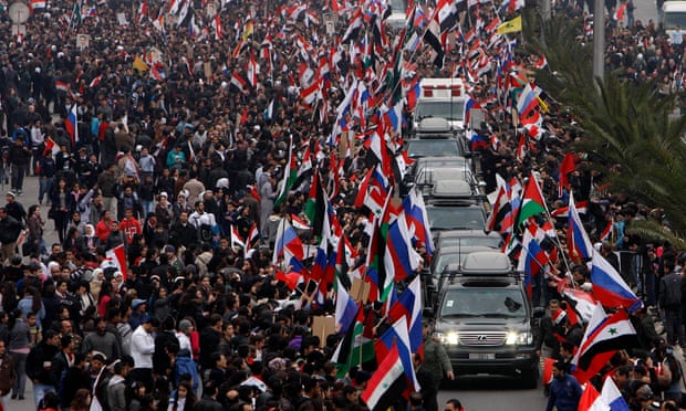Pro-Assad supporters wave Syrian and Russian flags as they cheer a convoy believed to be transporting Russian diplomats in Damascus, Syria, in 2012. 
