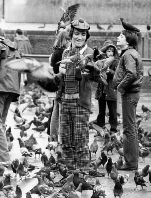 Clad in tartan, a Scottish football supporter feeds the pigeons in Trafalgar Square, London.