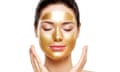 A woman relaxes wearing a gold face mask