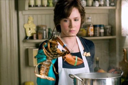 Adams in Julie & Julia is in a kitchen in an apron holding up a lobster ready to put it in the pot.