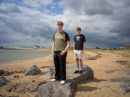 Two older teenage boys stand on a sandy beach