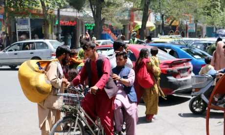 A family on the back of a flatbed van in traffic fleeing Kabul