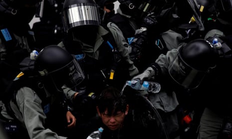 Police pour water on a protester who was pepper-sprayed while being detained in Sheung Shui, Hong Kong