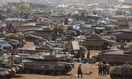 Soldiers stand next to scores of military vehicles, some of which are flying the Israel flag