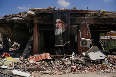 A banner with an image of late Hezbollah leader Hassan Nasrallah hangs from a destroyed building in Jibchit in the Nabatieh district.