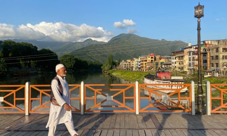 An elderly man walking across a bridge in Srinagar