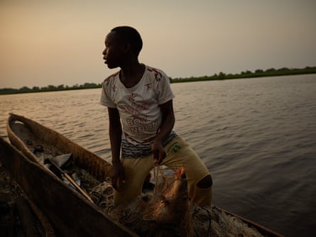 A boy sells his catch of the day mid-stream of the Congo River in Équateur province