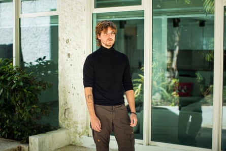 A man in a black turtleneck stands for a portrait
