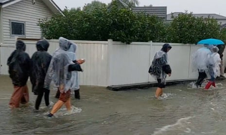 People walk on a flooded street after Elton John’s concert was cancelled due to bad weather in Auckland.