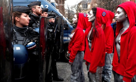 Women dressed as Marianne, a national symbol of the French republic, stand in front of officers.