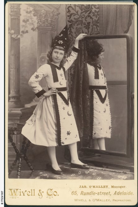 A black and white photo of a young girl wearing a dress and pointed hat