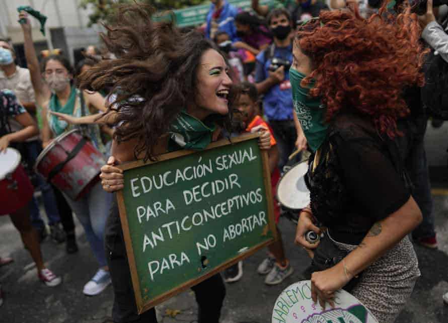 A woman holds a sign that reads in Spanish “Sex education to decide, contraceptives to avoid abortion,” as she jumps with another woman as part of the Global Day of Action for access to legal, safe and free abortion, outside the parliament in Caracas, Venezuela, 28 September