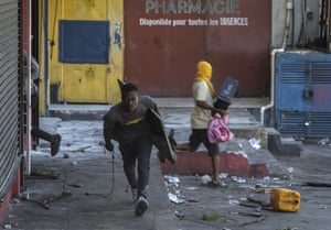 A man runs away with looted goods during a protest against fuel price hikes in Port-au-Prince, Haiti