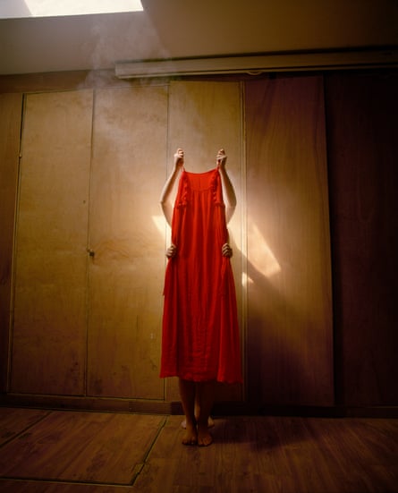 Colour photograph of two unidentified people holding up a red dress in front of them
