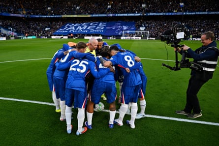 Chelsea players huddle around Paul Tierney, to a cameraman’s relish.