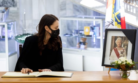 Jacinda Ardern wearing a black face mask gazes at a portrait of the Queen