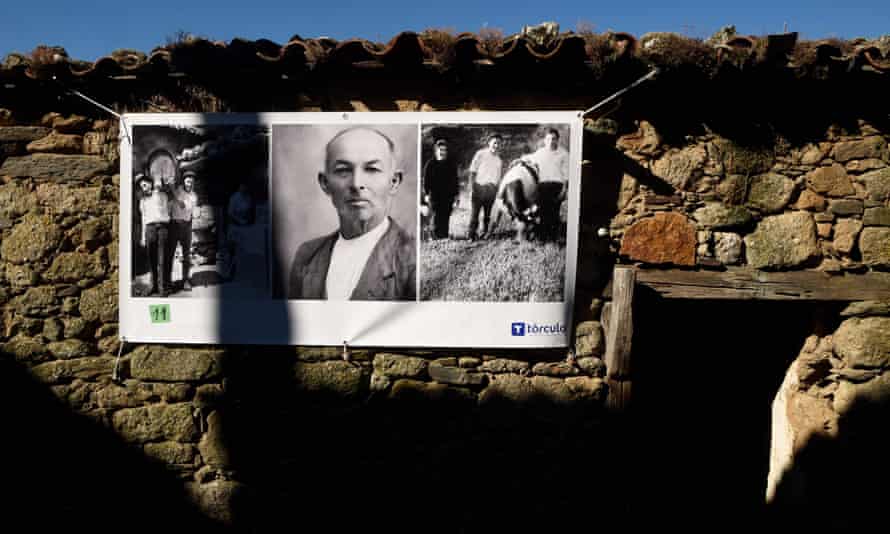 Photographs of former villagers are printed and displayed on a facade in the abandoned Galician village of Bexan