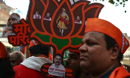 A BJP supporter carries a cutout of its logo with pictures of its leaders Narendra Modi, Amit Shah and Jagat Prakash Nadda.