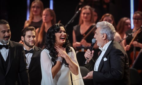 Russian soprano Anna Netrebko, in a white dress and diamond bracelet, performs onstage with Spanish tenor Placido Domingo during a gala concert at in the Kremlin Palace in Moscow, Russia.