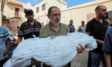 A mourner carries the body of a Palestinian child killed in an Israeli strike