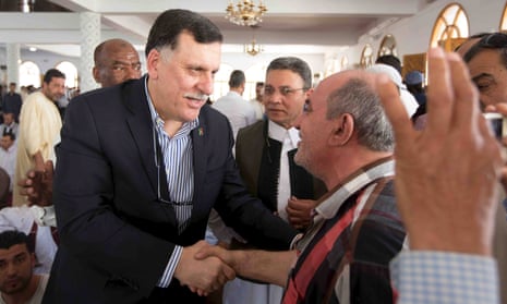 Fayez al-Sarraj (left) shakes hands with a man inside a mosque after Friday prayers in Tripoli earlier this month.