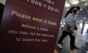 Visitors wearing face masks as a precaution against the coronavirus, walks past near a banner in Seoul, South Korea,