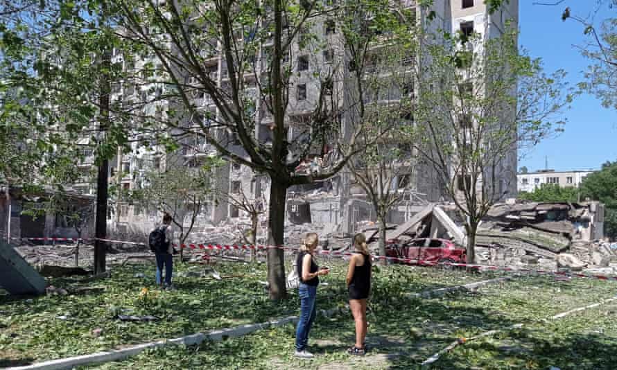 People near a residential building damaged by a Russian missile strike in the village of Serhiivka, Odesa.